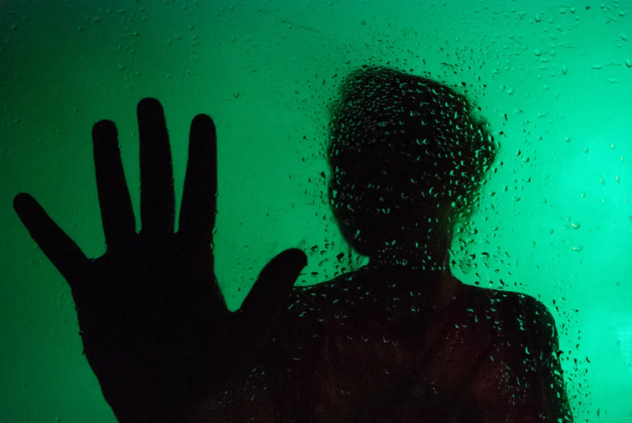 Hand auf regennassem Fenster